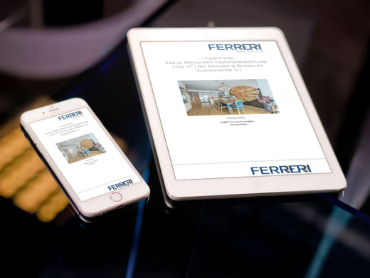 Exposé-Texte für luxuriöse Eigentumswohnung in Frankfurt am Main, aufgerufen auf iPad und Mobiltelefon, die auf einem Glastisch liegen.